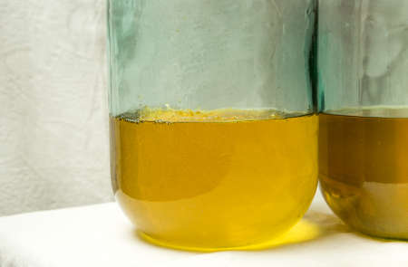 The process of making limoncello lemon liqueur at home. The filling of two ten-liter bottles with the necessary alcohol infused with lemon zest ends.の写真素材