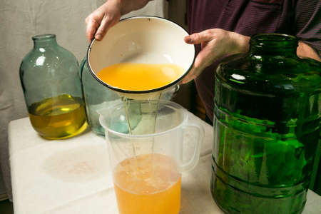 The man drains and strains the alcohol infused with lemon peel. The master measures the required...
