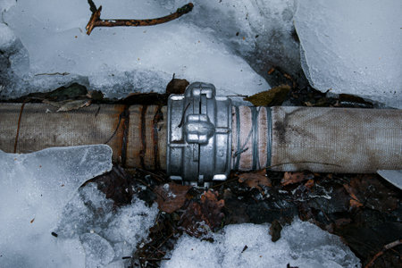 Winter. Everything is covered with snow. Leak in the connection of pipes pumping water out of the pond.の写真素材