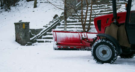 Snowplow removing snow on street after blizzard. Snowplow vehicle clears snowy road during blizzard. Snow clearing equipment. Tractor with snow plow blade clears road in city from fresh fallen snow.の写真素材