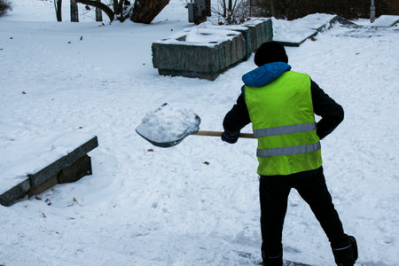 Municipal services are engaged in snow removal after a snowfall. A worker removes snow from the...