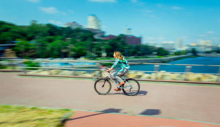 Motion blur. Young woman rides a bicycle along the city embankment.