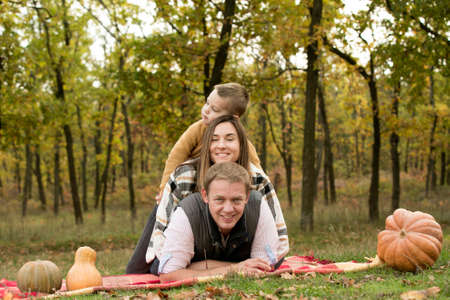 Fall. Close-up of happy family on the background of the autumn forest. Happy mom, dad and son are smiling.の写真素材