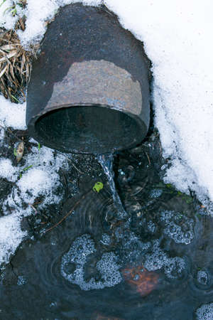 Spring is coming. The snow starts to melt. The pipe and the melting snow flows like a stream of water in it.の写真素材