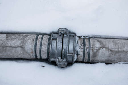 Winter. Everything is covered with snow. Leak in the connection of pipes pumping water out of the pond.の写真素材