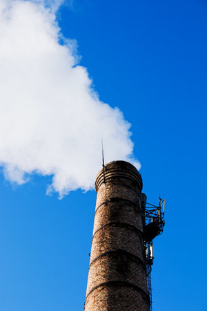 Smoke from chemical factory chimney on cloudy sky background. Ecology theme.の写真素材