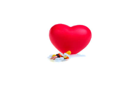 Red heart and spoon dispenser with capsules and pills on a white background. Isolate. Healthy...