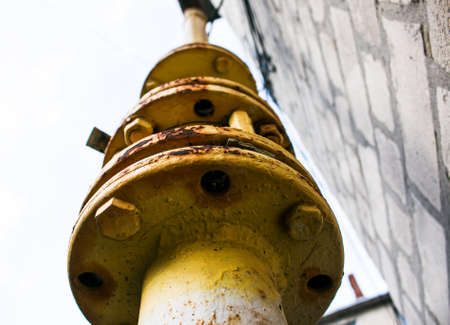 Yellow gas pipe with valve open close goes along the facade of a multi-storey building. House connected to gas for domestic use.の写真素材