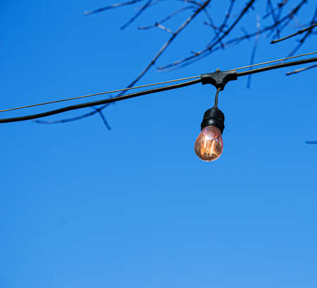 Close-up look-up view of street lighting with light comes on during the daytime. Concept for waste of electricity.の写真素材