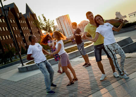 Dnepropetrovsk, Ukraine - 08.08.2017: Joyful townspeople dance on the square in the city at sunset. Three couple of young people are happy to dance.のeditorial素材