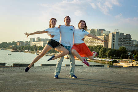 Dnepropetrovsk, Ukraine - 09/08/2017: Joyful townspeople dance on the square in the city at dawn. A young guy and two girls are happy to dance.のeditorial素材