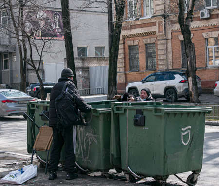 Dnepropetrovsk, Ukraine - 03.21.2021: A man drinks alcohol from a bottle on the street. Two homeless men found a bottle with the remnants of alcohol in the trash.のeditorial素材