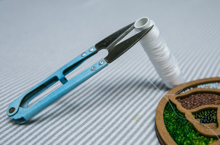 Weaving from beads. A box with beads and a skein of thread and scissors. Selective focus.