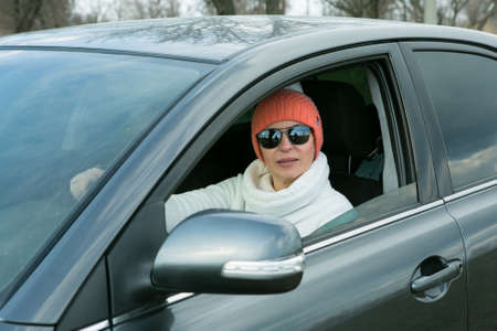 Portrait of a beautiful woman driving a car. A woman often drives out of town by car. In the...