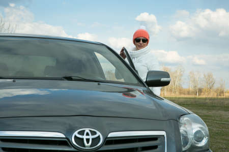 Dnepropetrovsk, Ukraine - 08.04.2021: Portrait of a beautiful woman near the car. The woman often travels out of town by car. In the face of the coronavirus pandemic, outdoor walks are essential.のeditorial素材