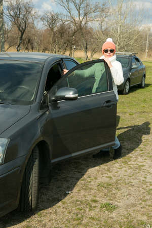 Portrait of a beautiful woman near the car. The woman often travels out of town by car. In the face...