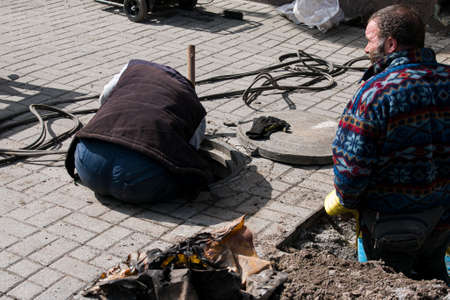 Dnepropetrovsk, Ukraine - 03.26.2021: Water utility workers open an old manhole and replace old rusty pipes with new ones.のeditorial素材
