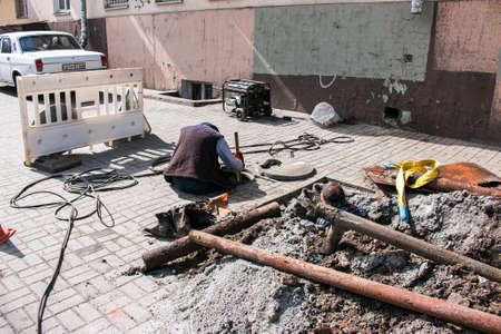 Dnepropetrovsk, Ukraine - 03.26.2021: Water utility workers open an old manhole and replace old rusty pipes with new ones.のeditorial素材