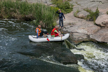 Tokovsky waterfall, Kamenka river, Ukraine - 05.16.2021: Concept of active recreation. A group of young people is rafting down the river.のeditorial素材