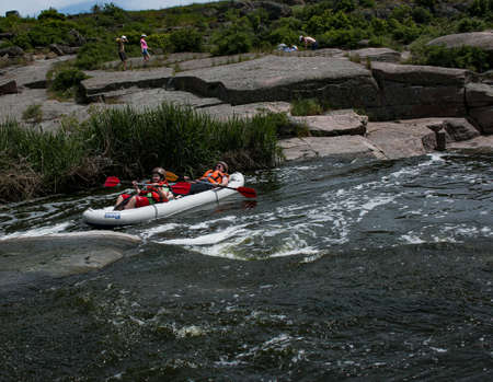 Tokovsky waterfall, Kamenka river, Ukraine - 05.16.2021: Concept of active recreation. A group of young people is rafting down the river.のeditorial素材