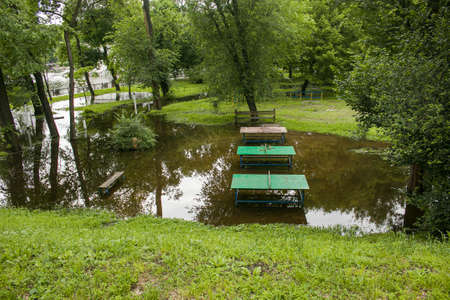 Public park drenched in rain. Water logged park.Wet benches. Park filled with water after rain.Empty park after heavy rain.の写真素材