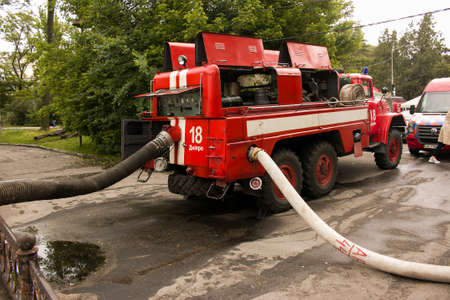 Flood in a city park after heavy rains. Fire truck with water pumping hoses eliminates the disaster.
