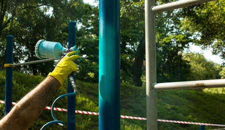 Workers of the municipal city service paint pipes on a playground in the park. Spray painting from a balloon.の写真素材