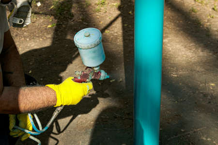 Workers of the municipal city service paint pipes on a playground in the park. Spray painting from a balloon.の写真素材
