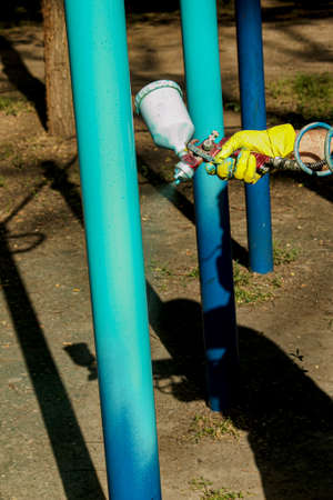 Workers of the municipal city service paint pipes on a playground in the park. Spray painting from a balloon.の写真素材