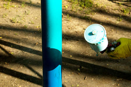 Workers of the municipal city service paint pipes on a playground in the park. Spray painting from a balloon.の写真素材
