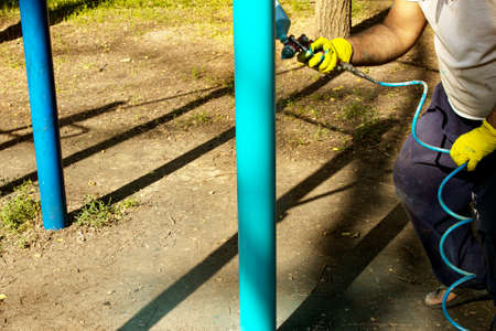 Workers of the municipal city service paint pipes on a playground in the park. Spray painting from a balloon.の写真素材