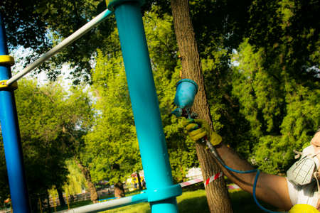 Workers of the municipal city service paint pipes on a playground in the park. Spray painting from a balloon.の写真素材