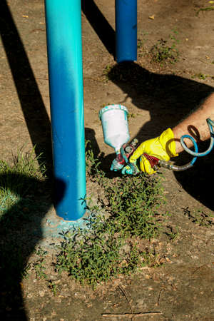 Workers of the municipal city service paint pipes on a playground in the park. Spray painting from a balloon.の写真素材