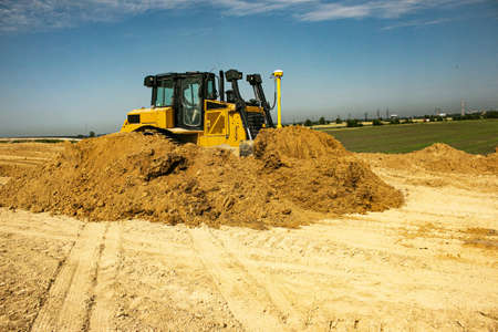 Asphalt road construction process. The bulldozer levels and compacts the clay soil for the base of...