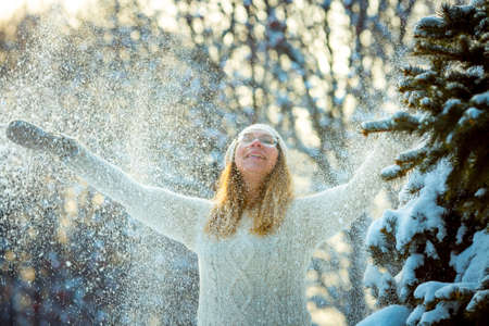 Happy woman plays with a snow in sunny winter day. Girl enjoys winter, frosty day. Playing with snow...