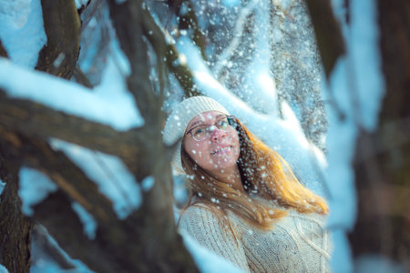Happy woman plays with a snow in sunny winter day. Girl enjoys winter, frosty day. Playing with snow on winter holidays, a woman throws white, loose snow into the air. Walk in winter forest.の写真素材
