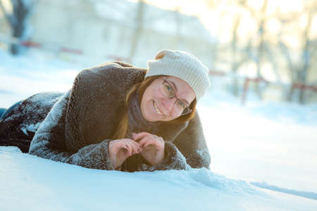Happy woman plays with a snow in sunny winter day. Girl enjoys winter, frosty day. Playing with snow on winter holidays, a woman throws white, loose snow into the air. Walk in winter forest.の写真素材