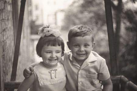 USSR - CIRCA 1971: an antique photo show of a little girl with a bow and a boy laughing merrily. The boy hugged the girl.の写真素材
