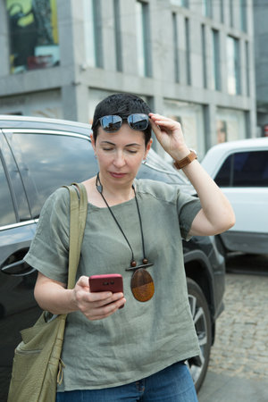 Attractive middle-aged woman with a phone in the city. Beautiful woman browsing phone