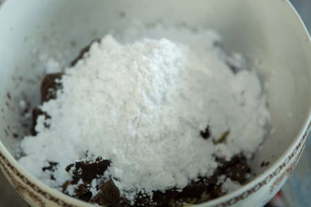 Step-by-step process of making chocolates from dark chocolate and cherries in cognac at home. A container with grated cocoa, cocoa butter and powdered sugar.