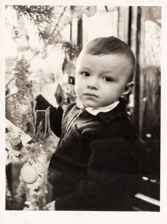 Dnepropetrovsk, USSR - CIRCA 1965: Black and white portrait of a little boy near a New Year tree.の写真素材