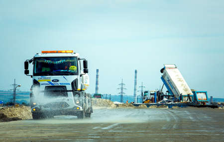 Dnepropetrovsk, Ukraine - 08/17/2021: Construction of a new bypass road around the city. A special machine washes away dirt and dust before paving.のeditorial素材