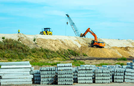 Dnepropetrovsk, Ukraine - 08.17.2021: The excavator works at a construction site in earthworks. Excavator on road works digs the ground. Construction equipment for earthworksのeditorial素材