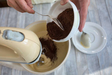 Cake making process. Female hands add cocoa to the mixer bowl for making dough. Step by step recipe for chocolate cake. Series. Baking concept.の写真素材