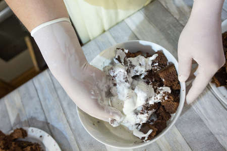 Cake making process. Female hands in culinary gloves form a chocolate cake with sour cream. Step by...