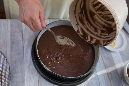 Cake making process. The dough is ready. The cook puts the finished dough into a baking dish. Step by step recipe for chocolate cake. Series. Baking concept.の写真素材