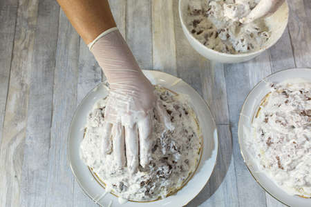 Cake making process. Female hands in culinary gloves form a chocolate cake with sour cream. Step by...