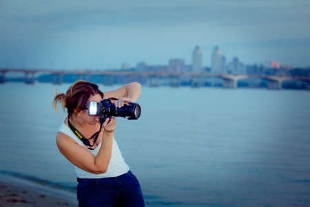 Dnepropetrovsk, Ukraine - 09.24.2014: A beautiful woman photographer is doing her job. A professional camera allows you to make good reports.のeditorial素材