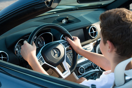 Dnepropetrovsk, Ukraine - 08.24.2021: Closeup on male hands driving Mercedes Benz car luxury transportation lifestyle. Mercedes Benz SL550 convertible on the road.のeditorial素材