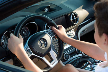 Dnepropetrovsk, Ukraine - 08.24.2021: Closeup on male hands driving Mercedes Benz car luxury transportation lifestyle. Mercedes Benz SL550 convertible on the road.のeditorial素材